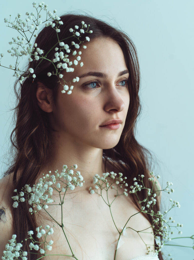 portret kobiety z kwiatami artystyczny portret kobiecy subtelna fotografia portretowa kobieta z delikatnymi kwiatami naturalne piękno romantyczny portret fotografia w ciepłym świetle kobieta trzymająca kwiaty