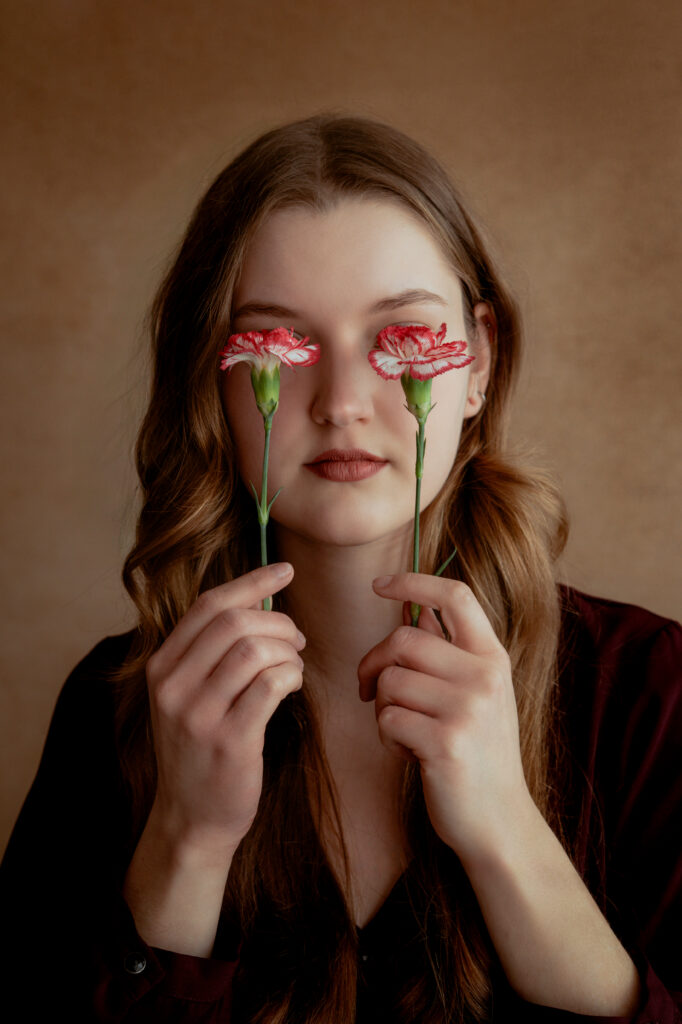 portret kobiety z kwiatami artystyczny portret kobiecy subtelna fotografia portretowa kobieta z delikatnymi kwiatami naturalne piękno romantyczny portret fotografia w ciepłym świetle kobieta trzymająca kwiaty