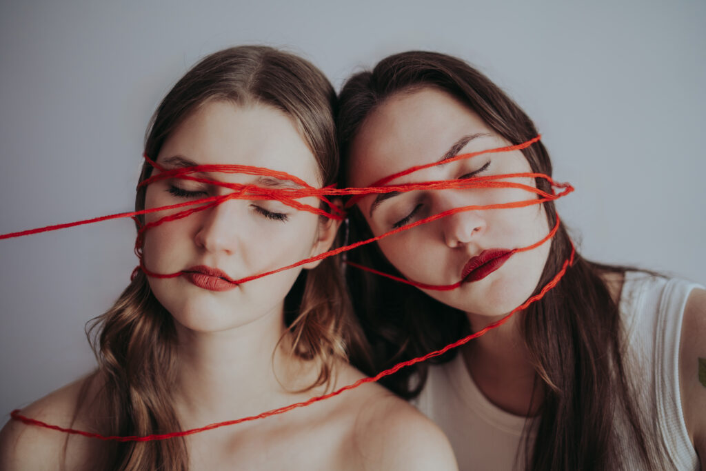 portret artystyczny kobiety fotografia konceptualna czerwona nić na twarzy symbolika nici losu motyw przeznaczenia w sztuce kobieta z zamkniętymi oczami minimalistyczny portret fotografia z przesłaniem artystyczna fotografia kobieca emocjonalny portret